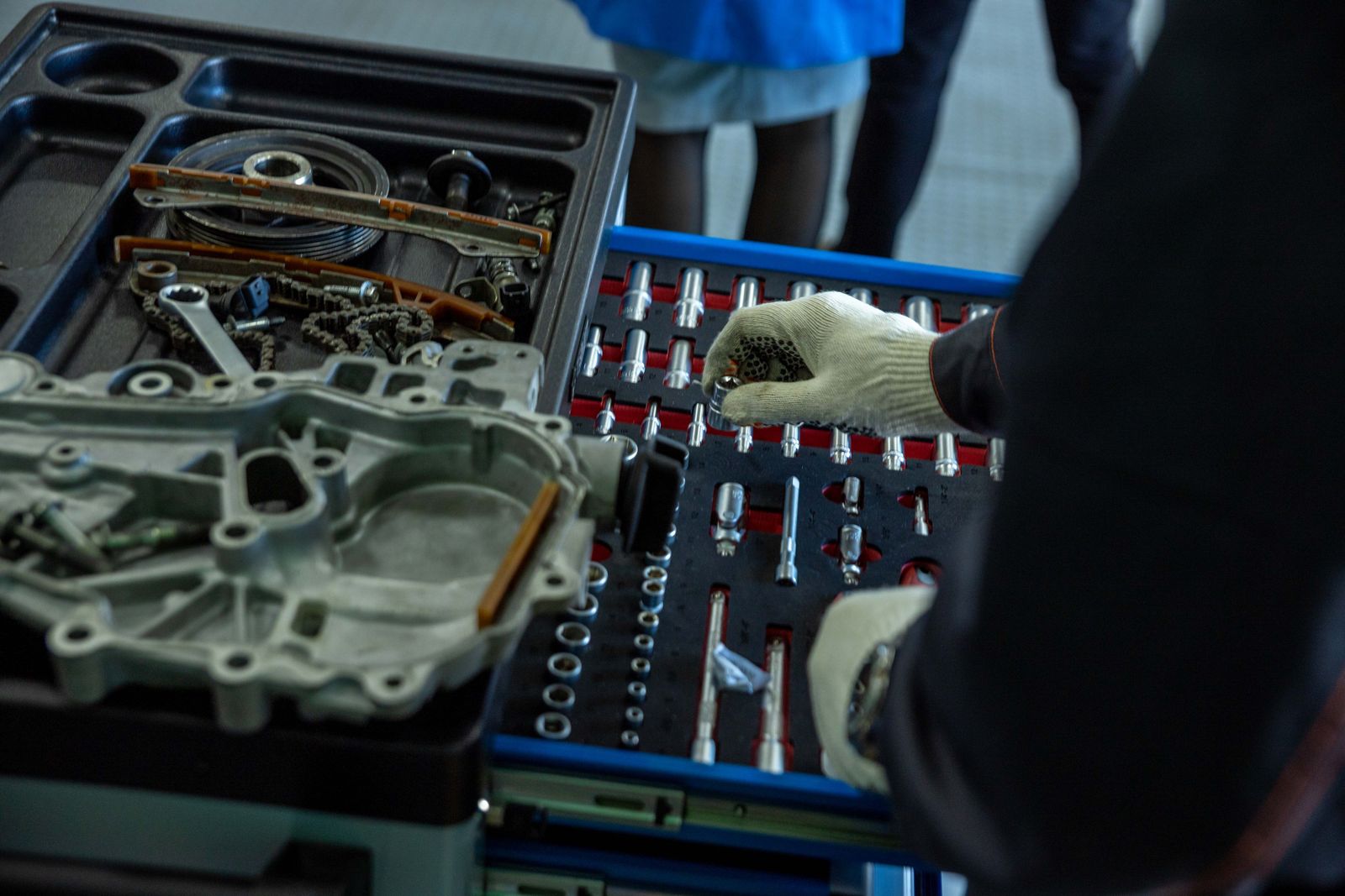 A mechanic organizing engine parts and tools in a workshop.